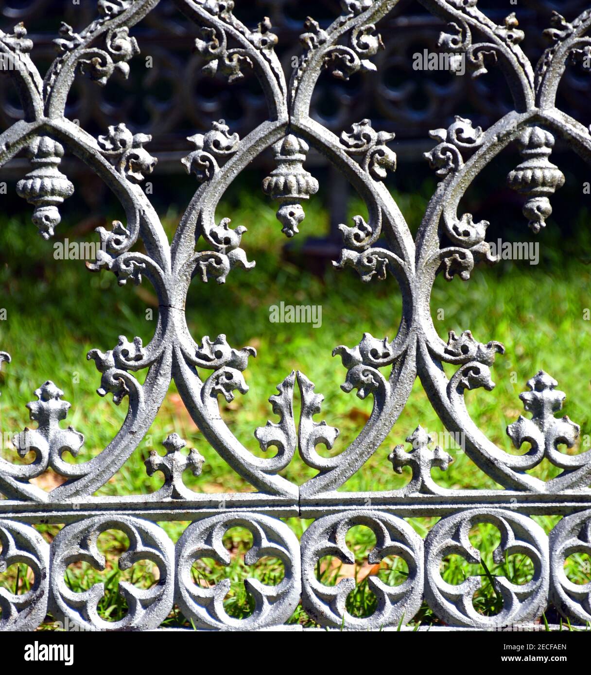 Background image of an old cemetery fence.  Fence is metal with an elaborate, silver colored design. Stock Photo