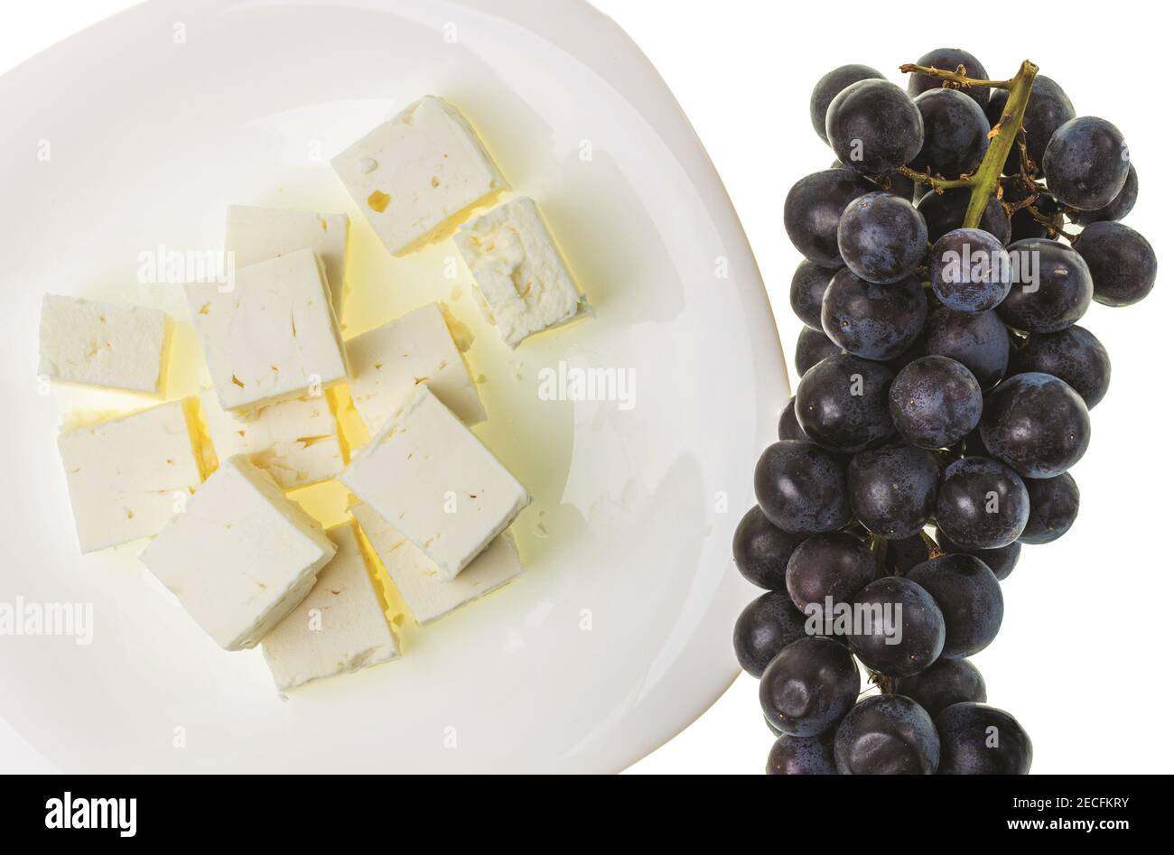 Close up view of black grape and brined white Feta cheese on white background. Healthy eating concept. Stock Photo