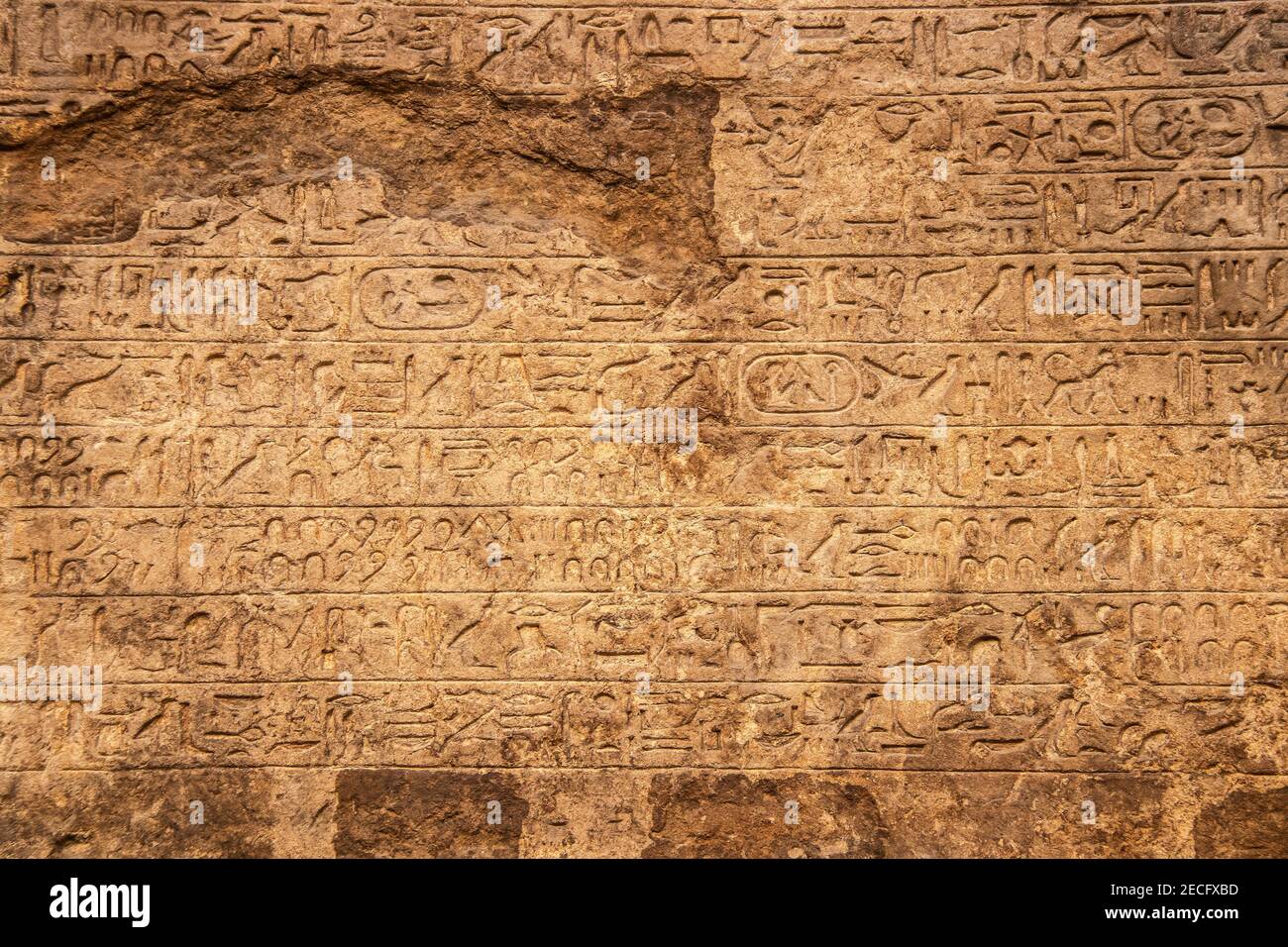 Background - Carved ancient Egyptian writing or hieroglyphics-sacred carvings or mdju netjer meaning words of the gods - in horizontal rows - damaged Stock Photo