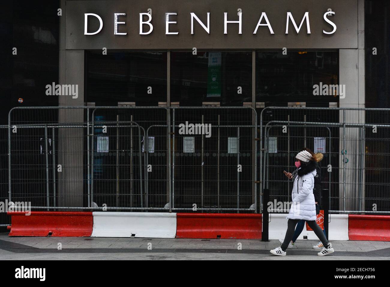 Dublin, Ireland. 13th Feb, 2021. A woman wearing a face mask walks past a closed Debenhams store on Henry Street. Credit: SOPA Images Limited/Alamy Live News Stock Photo