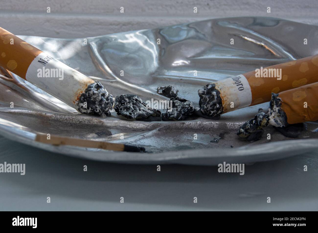 A close-up image of a Marlboro cigarette laying in an ashtray. Stock Photo