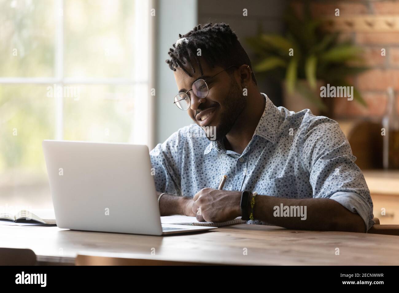 Close up African American man using laptop, taking notes Stock Photo