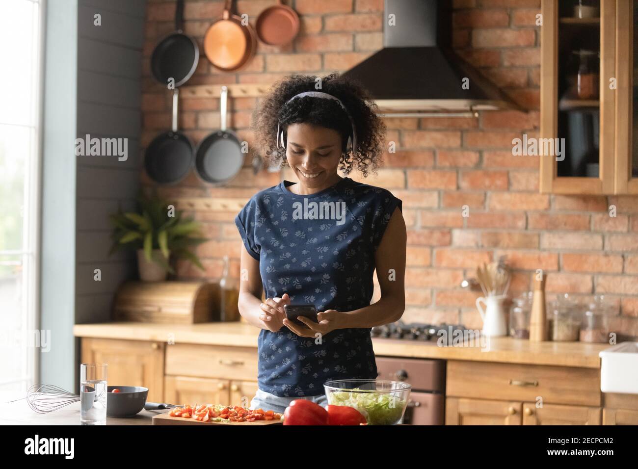 Smiling African American woman wearing headphones cooking in kitchen Stock Photo Alamy