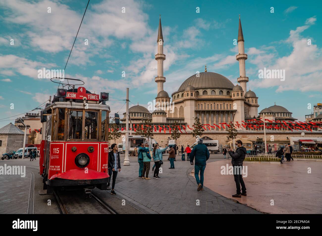 Istanbul, Turkey - February 9, 2021 - people, vintage red tramway streetcar and mosque on Taksim Square Stock Photo