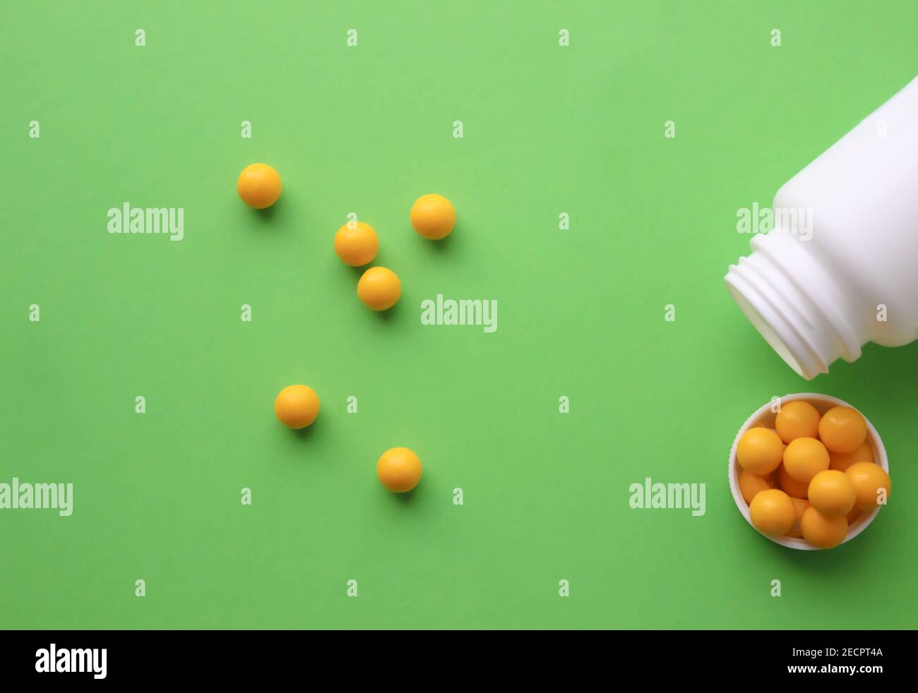Yellow round tablets on a green background. Yellow vitamins from a