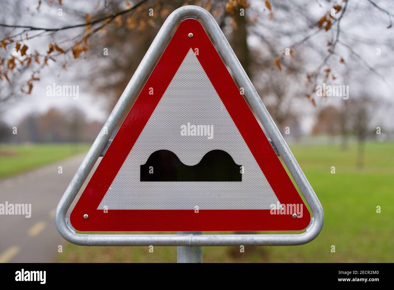 Traffic sign bumpy road with tree in the background. Stock Photo