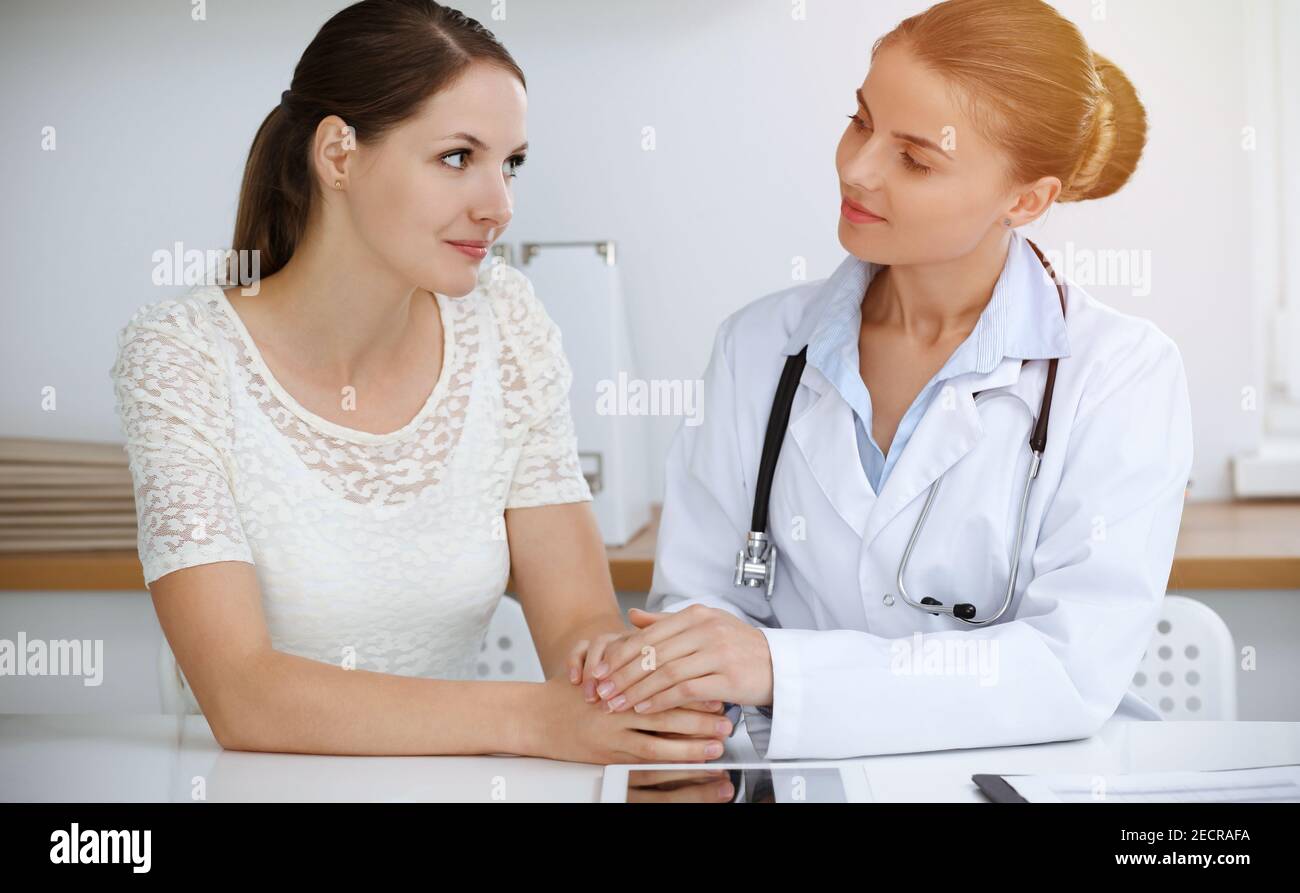 Woman-doctor reassuring her female patient while sitting at the desk ...