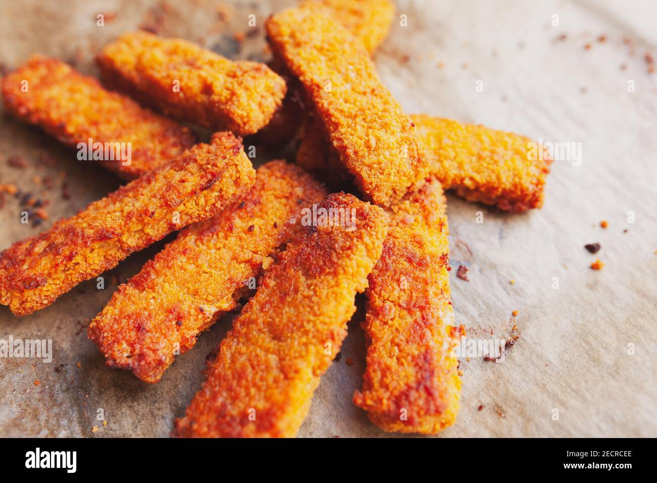 Bunch of deep fried, crispy fish fingers on greasy parchment paper Stock Photo