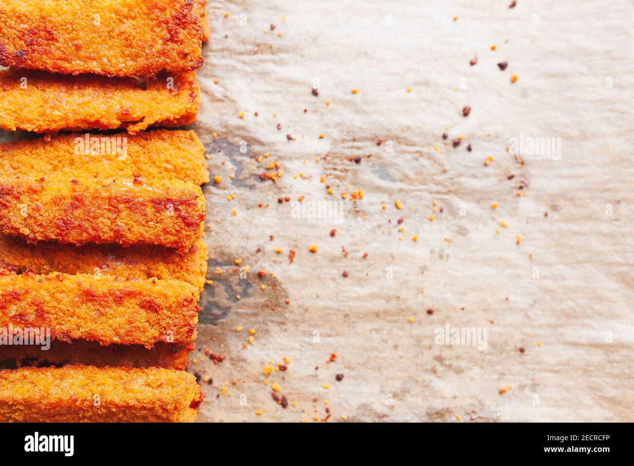 Deep fried fish fingers on greasy parchment paper and some crumbs, copy space on right side Stock Photo