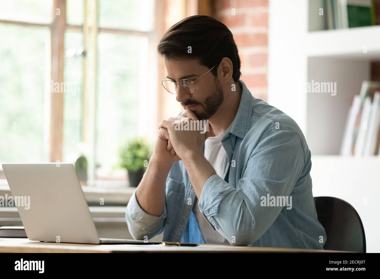 Pensive male employee work on laptop in office thinking Stock Photo - Alamy