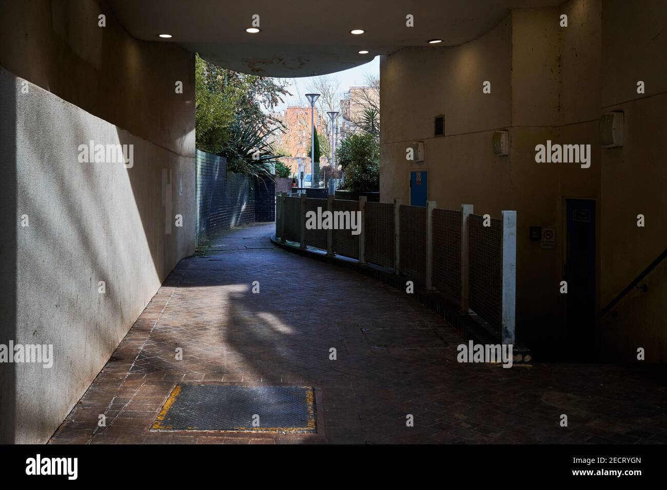 London,UK - 13 Feb 2021 : Walkway though covered walkway through built up estate through to green area Stock Photo