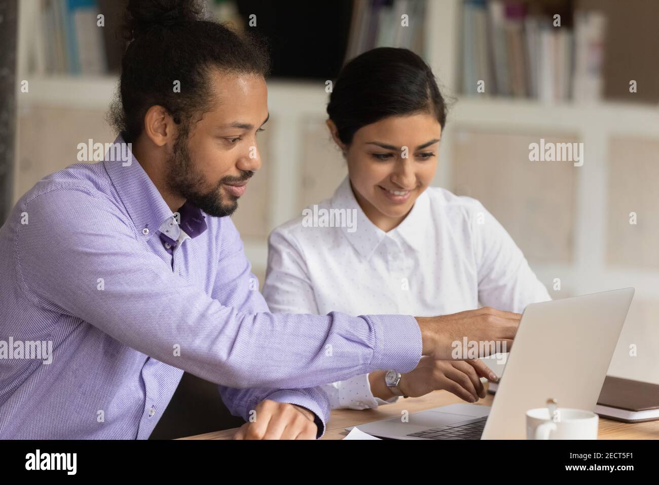Smiling multiethnic colleagues work together on computer Stock Photo