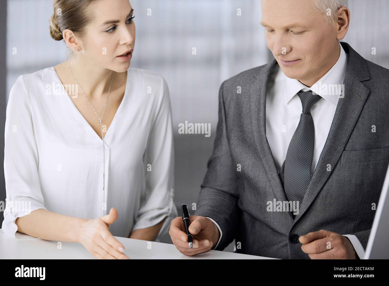 Elderly businessman and woman sitting and communicating in office. Adult business people or
