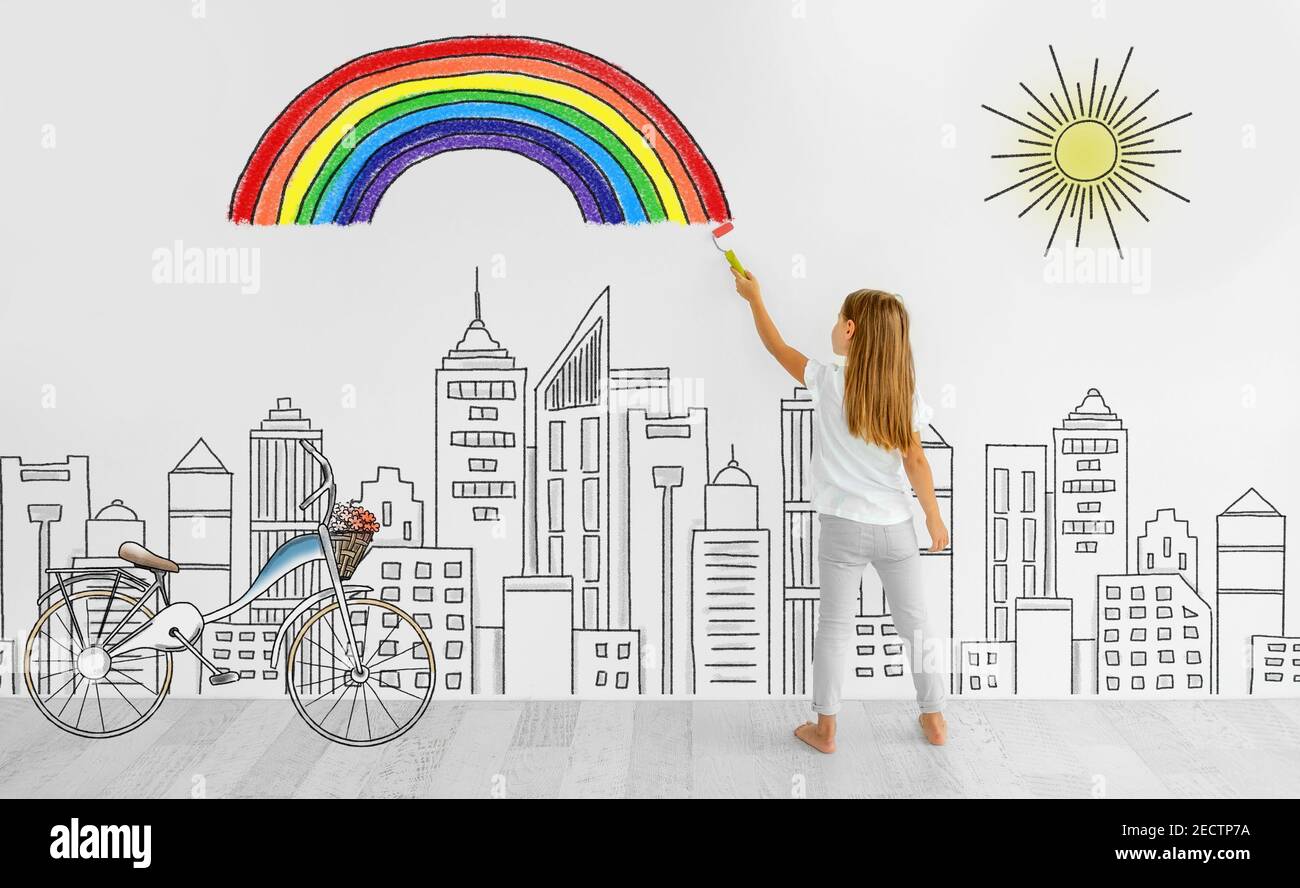 Little girl drawing rainbow on white wall Stock Photo