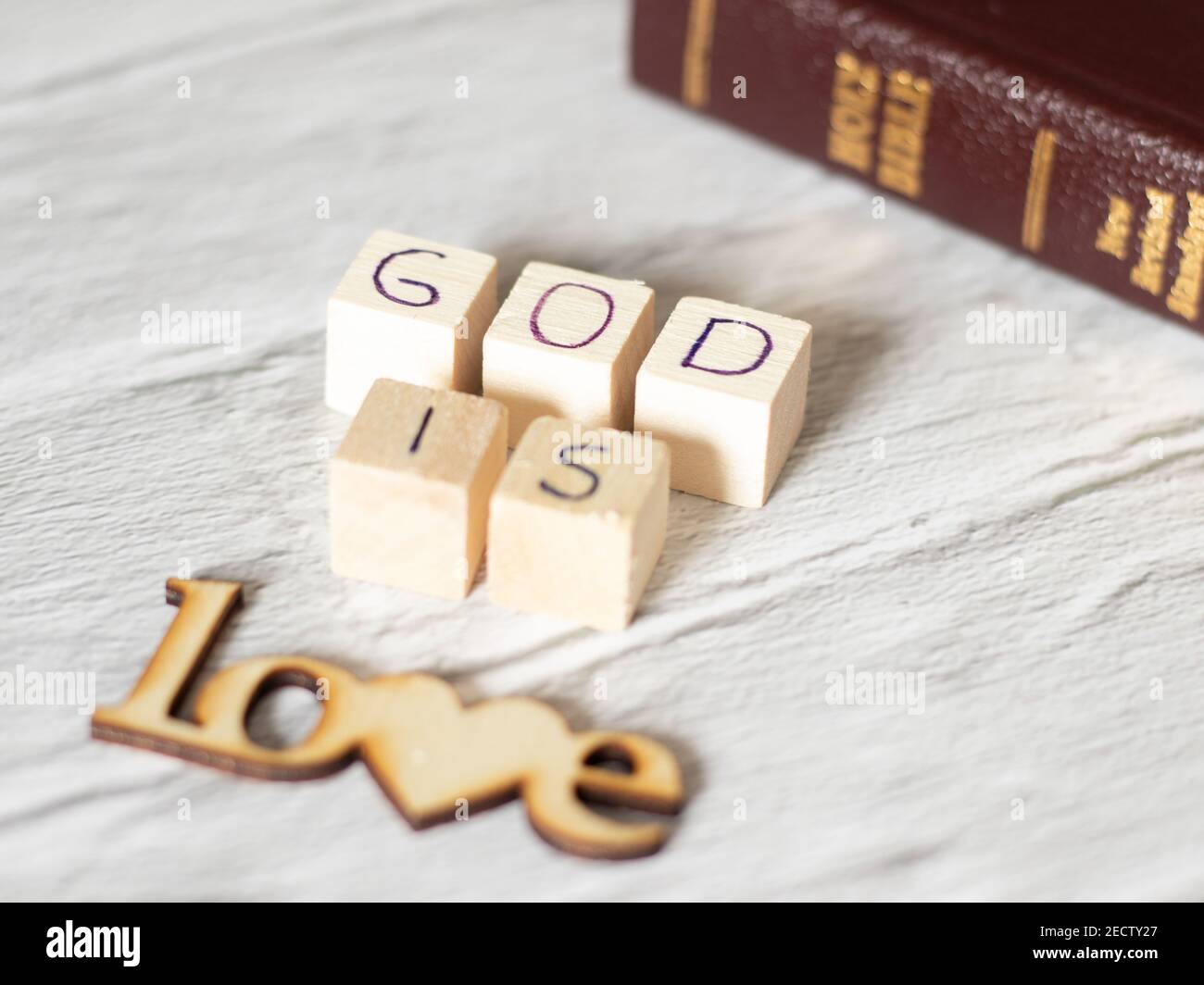 God is Love. Wooden text and Holy Bible with gold letters. God the Father and Jesus Christ love us all. Salvation, forgiveness, redemption, faith. Stock Photo
