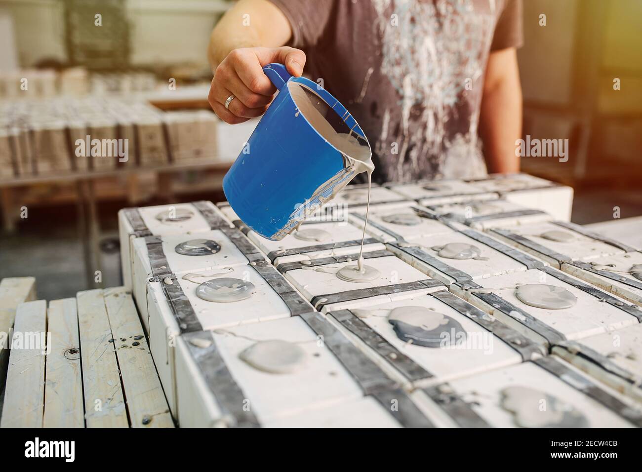 Man pouring liquid clay in molds for casting cups and other tableware