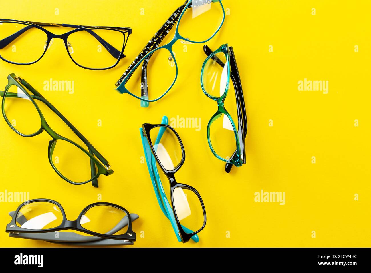 Many stylish glasses on a yellow background. Health, style and business concept. Eyesight correction. Space for text. Stock Photo