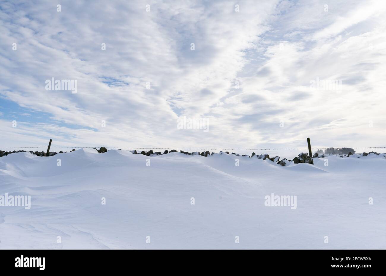 Snow drift against a dry stone wall in Northumberland, UK Stock Photo