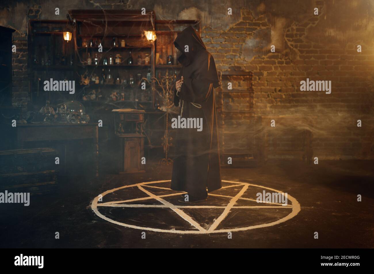 Male exorcist in hood standing in the magic circle Stock Photo