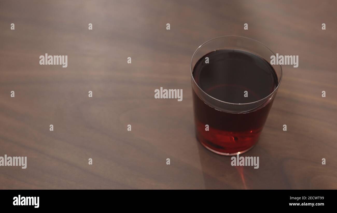 red drink in tumbler glass on walnut table with copy space, wide photo