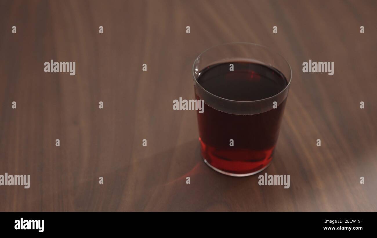 red drink in tumbler glass on walnut table with copy space, wide photo