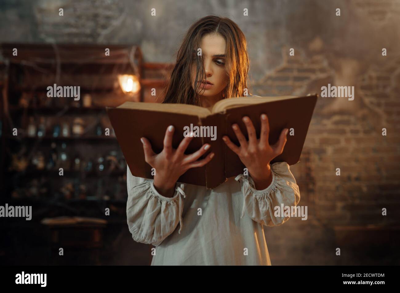 Young demonic woman holds book of spells Stock Photo
