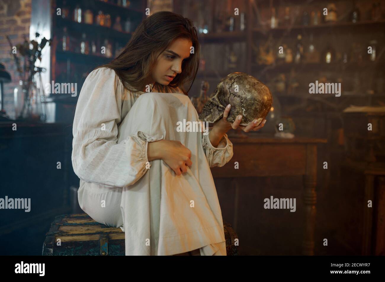 Scary demonic woman holds human skull, exorcism Stock Photo