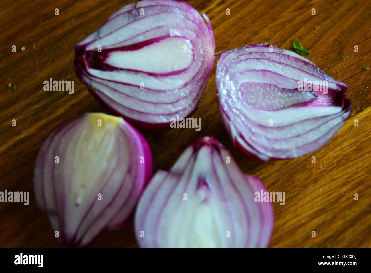 Two red onions cut in half and lie on a brown wooden kitchen board ...