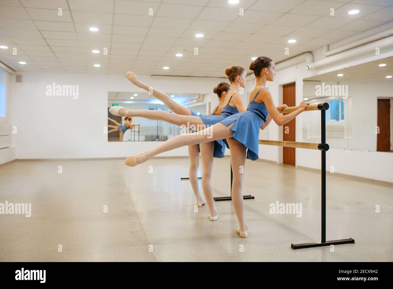 Three young ballerinas rehearsing at the barre Stock Photo