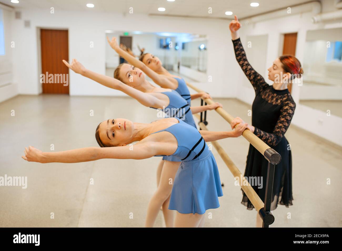Teacher works with ballerinas at barre in class Stock Photo