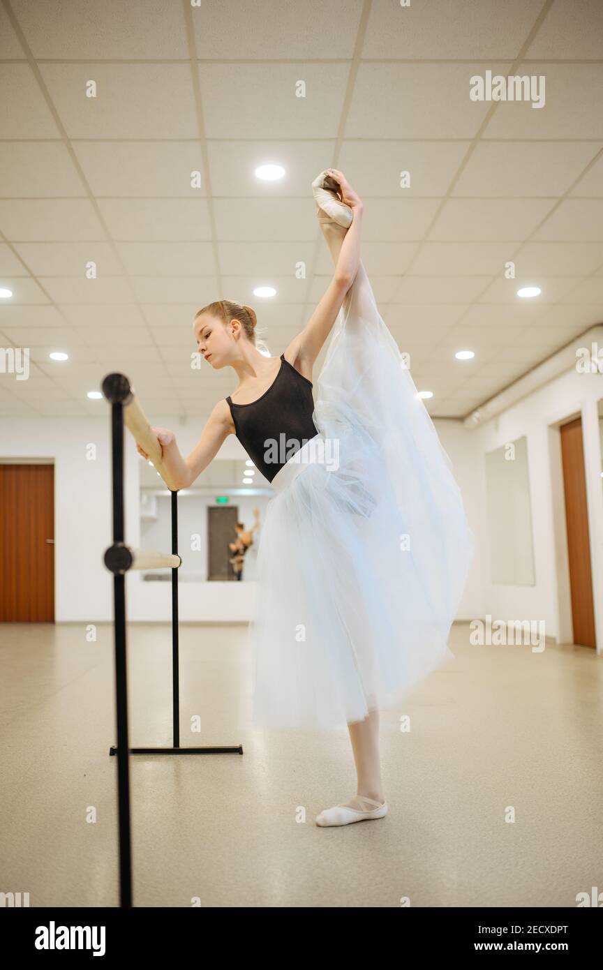 Elegant young ballerina works at barre in class Stock Photo