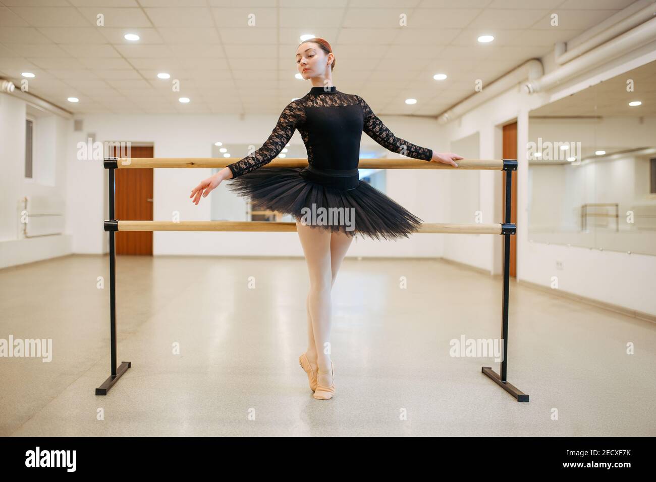 Ballerina poses at barre in class, ballet school Stock Photo