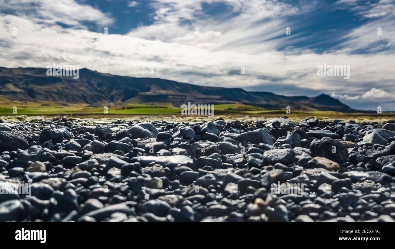 Closeup view of Icelandic riverbed stones with mountains on the background Stock Photo