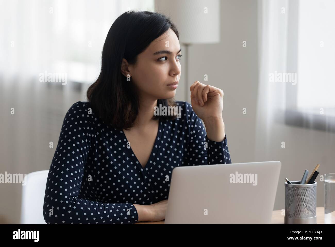 Thoughtful vietnamese female look aside of laptop visualize work result Stock Photo