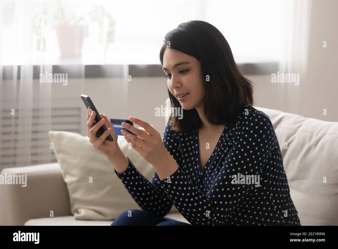 Attentive asian woman read plastic card data to pay online Stock Photo