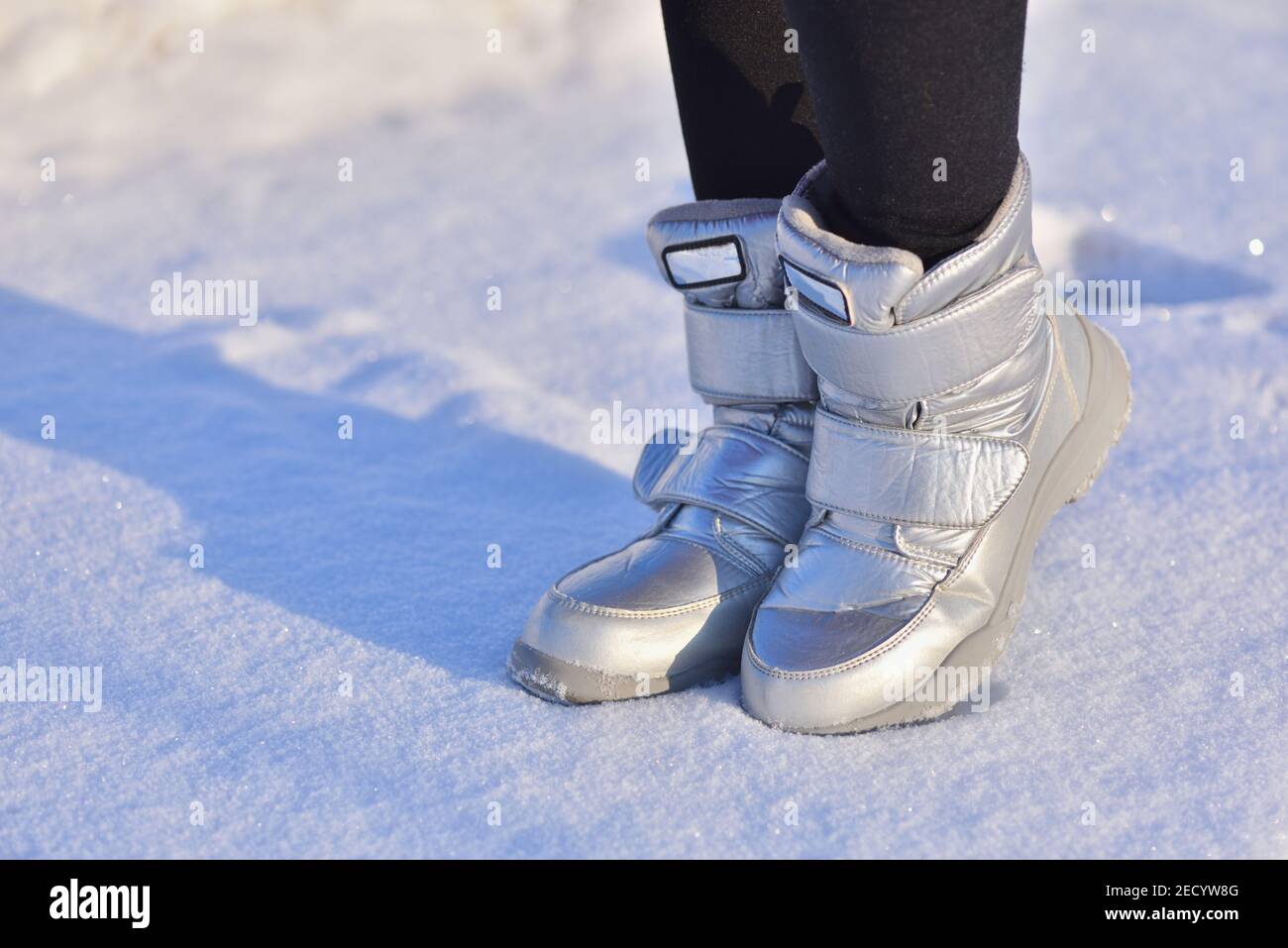 Children's winter boots in silver color on the snow Stock Photo