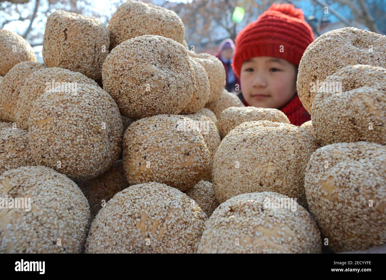 (210214) -- BEIJING, Feb. 14, 2021 (Xinhua) -- A child buys 'sugar melon', a Lunar New Year snack made of malt sugar, glutinous rice and sesame, in Yiyuan County, east China's Shandong Province, Feb. 10, 2015. Lunar New Year ranks among the most important festivals in China, and the celebrations are multifaceted, including food. When the Lunar New Year comes, people across China make a variety of snacks which they believe will bring good fortune. (Photo by Zhao Dongshan/Xinhua) Stock Photo