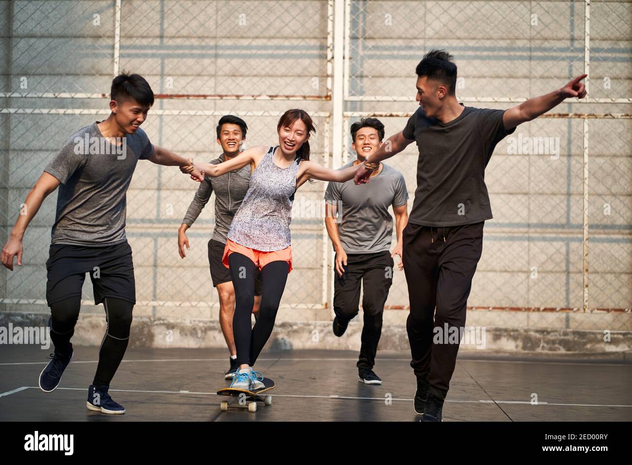 young asian adults men and woman having fun with skateboard outdoors Stock Photo