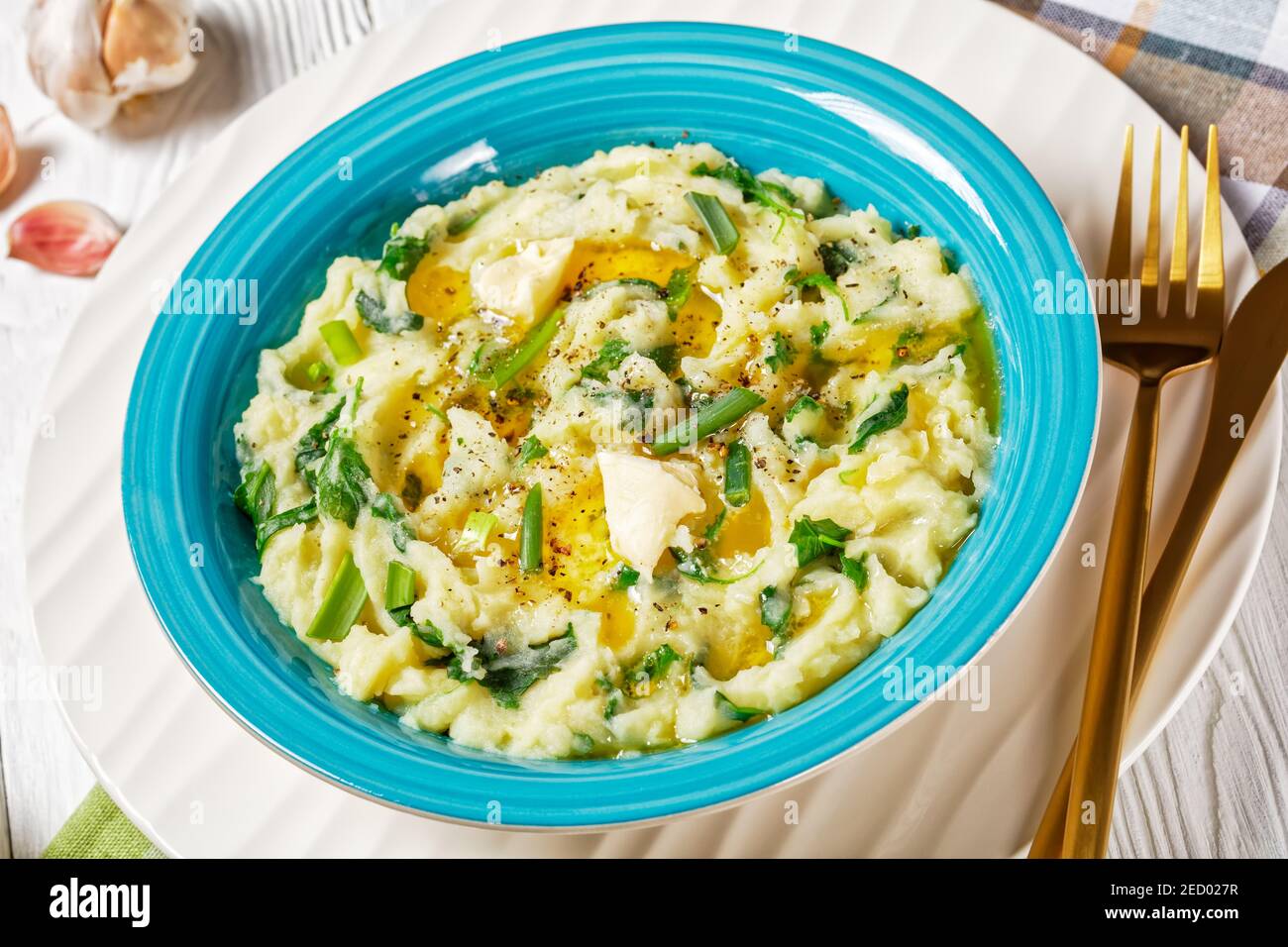 Irish colcannon traditional potato mash with kale, garlic, melted butter and spring onion served on a blue bowl, white counter plate on a white wooden Stock Photo