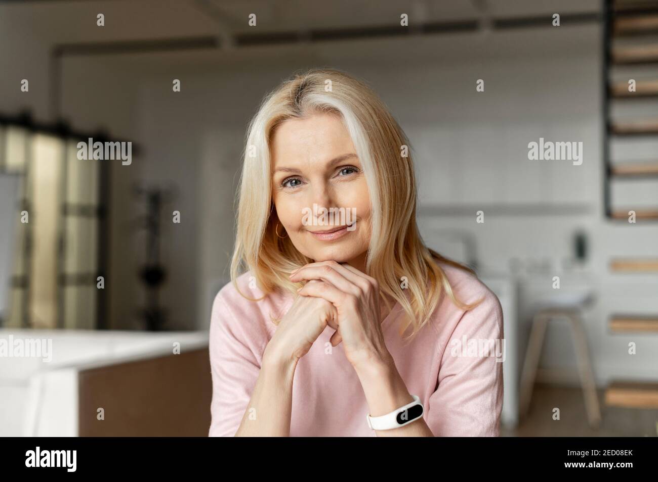 Elegant middle-aged woman with blond hair sitting at the camera,looking ...