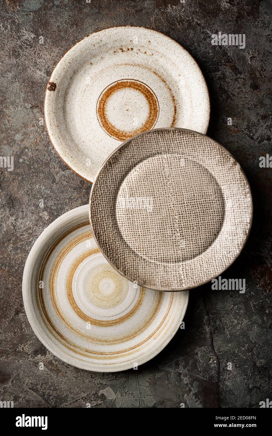 Three different homemade ceramic plates on dark gray background, top view Stock Photo