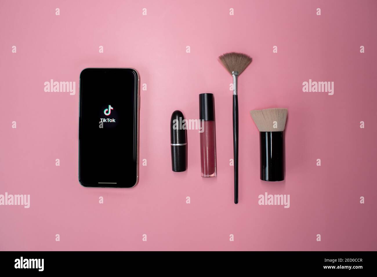 London, United Kingdom - February 14, 2021: iPhone showing the popular social media app Tik Tok with cosmetic makeup brushes and lipstick. Stock Photo
