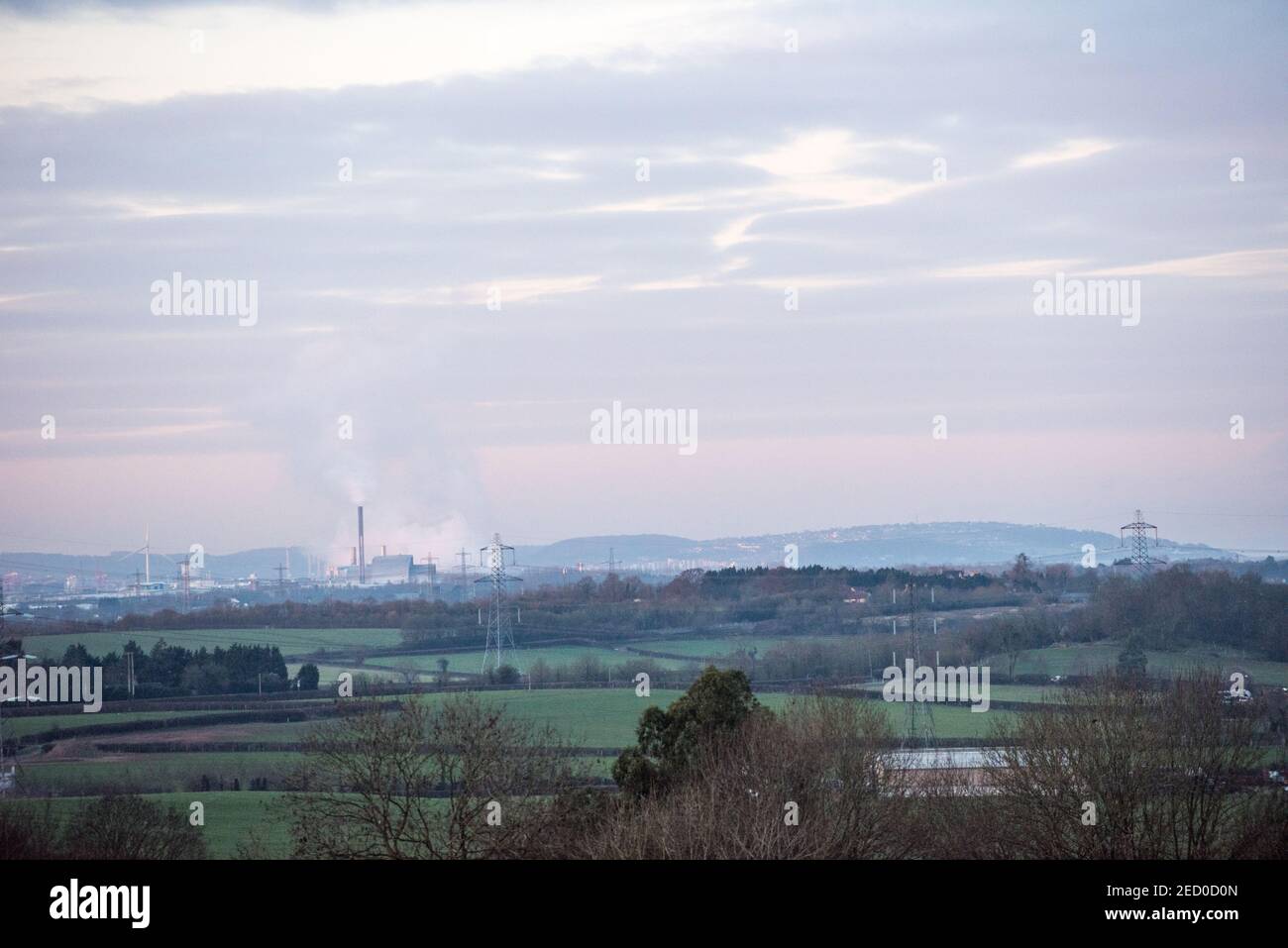 View across countryside to industrial Avonmouth and the Seabank Power Station pumping out plumes of steam, over wind turbines and electricity pylons Stock Photo