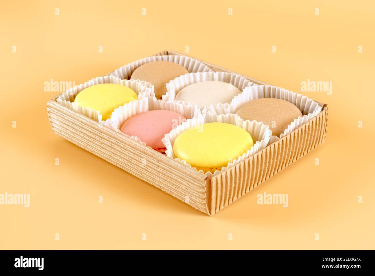Colored macaroons pack in craft cardboard box on beige background Stock Photo