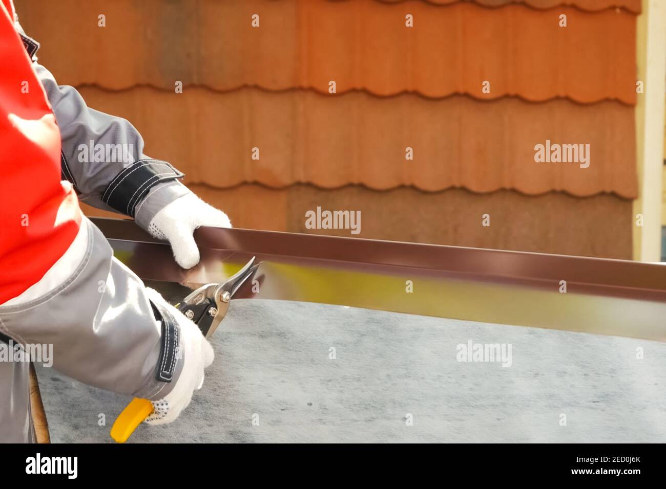 Worker shears a sheet of roofing metal. Scissors for metal Stock Photo
