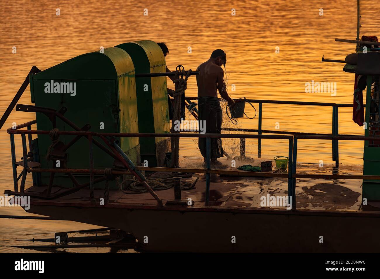 Monywa, Myanmar - December 22, 2019: View of a man taking a shower on his boat before going to home Stock Photo