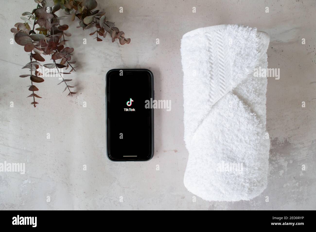 London, United Kingdom - February 14, 2021: iPhone showing the popular social media app Tik Tok with a spa towel and eucalyptus plant. Stock Photo