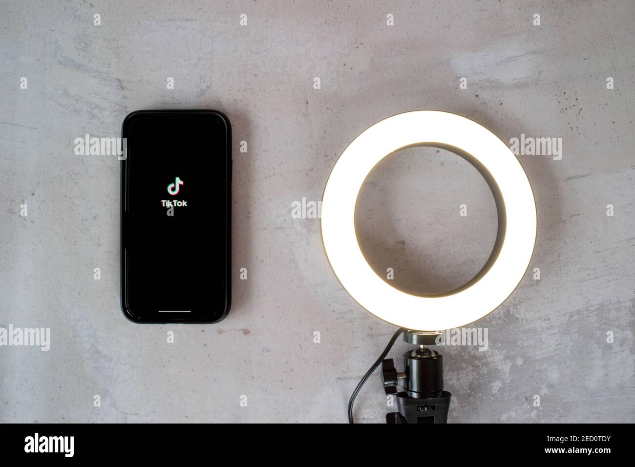 London, United Kingdom - February 14, 2021: iPhone showing the popular social media app Tik Tok with a camera ring light on a stone background. Stock Photo