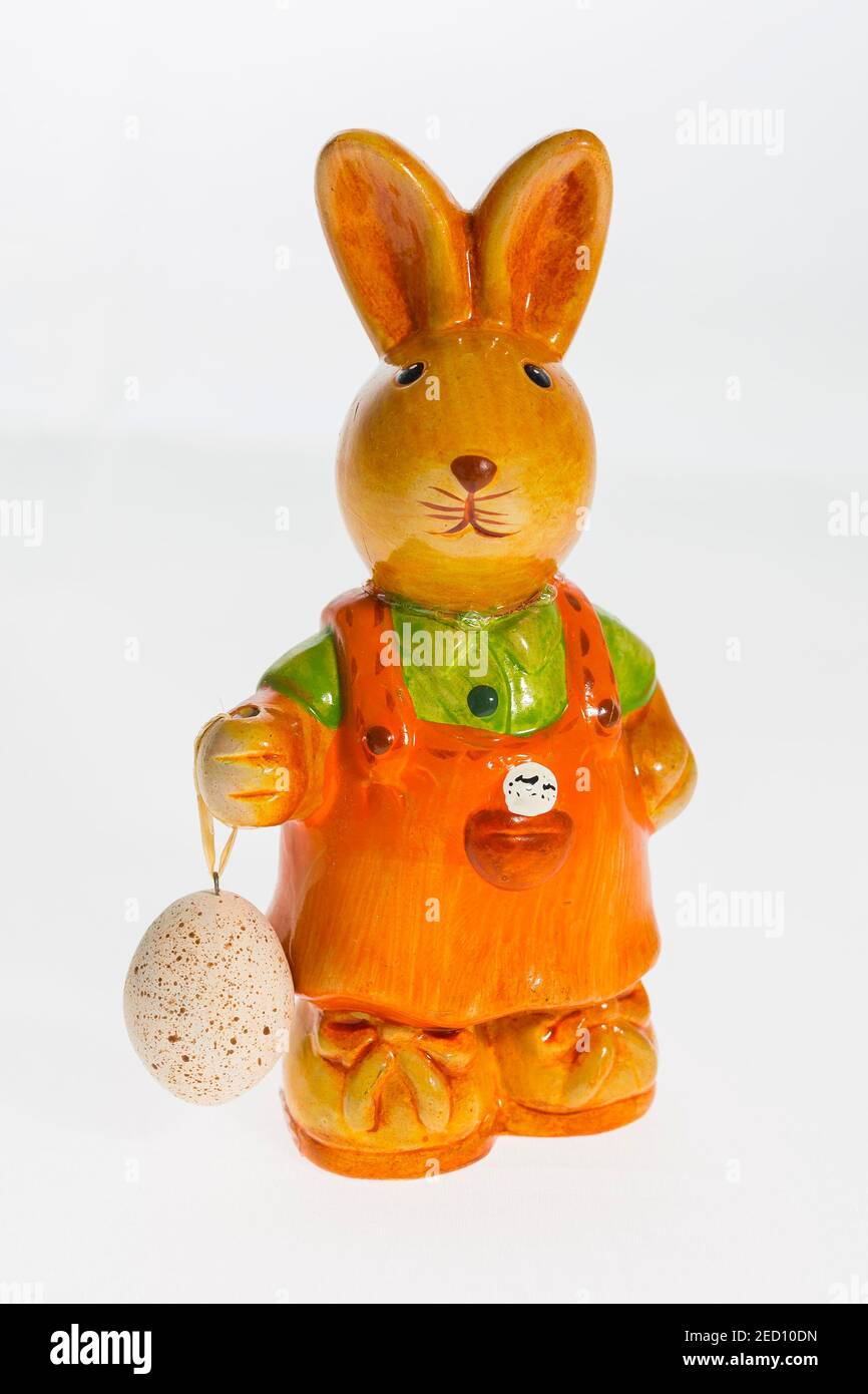 Brown Easter bunny figure with egg in hand against white background Stock Photo