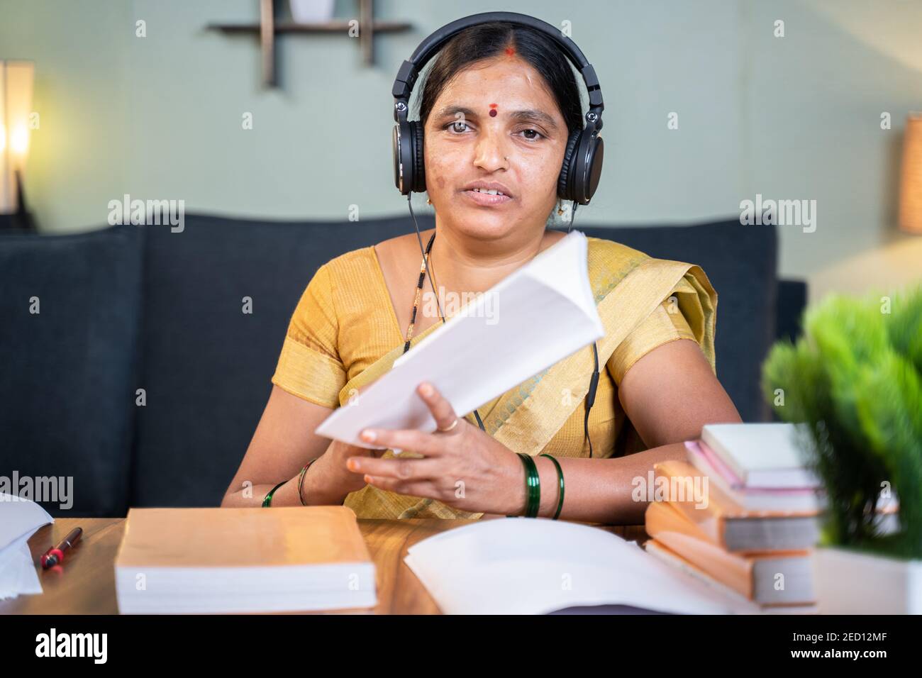 Indian woman busy explaining from book during online class by looking camera at home - Concept of e-teaching, Remote learning, virtual education Stock Photo